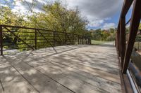 a wooden bridge over a paved path in the autumntime with fall foliage and a path winding through it