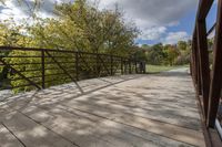 a wooden bridge over a paved path in the autumntime with fall foliage and a path winding through it