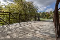 a wooden bridge over a paved path in the autumntime with fall foliage and a path winding through it