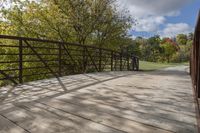 a wooden bridge over a paved path in the autumntime with fall foliage and a path winding through it