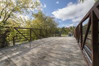 a wooden bridge over a paved path in the autumntime with fall foliage and a path winding through it