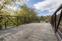 a wooden bridge over a paved path in the autumntime with fall foliage and a path winding through it