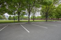 a car is parked at an empty parking lot with lots of trees and grass in the back of the picture