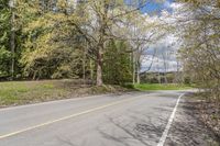 an empty road on the side of a wooded area with trees and rocks to the side of the road