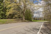 an empty road on the side of a wooded area with trees and rocks to the side of the road