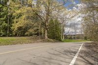 an empty road on the side of a wooded area with trees and rocks to the side of the road