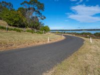 a curved road leading off into the ocean and water as it passes by on a sunny day