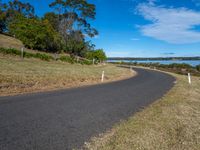 a curved road leading off into the ocean and water as it passes by on a sunny day