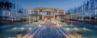 an outdoor bath with water fountain next to two glass walls and lamps at night time