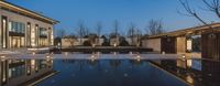 the swimming pool with candles around it at night, with beautiful houses in the background