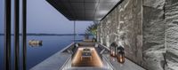 an outdoor fireplace sitting in the middle of a balcony overlooking a lake with a stone wall