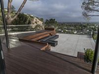 a deck with a fire pit on it and a balcony and overlooking the city below