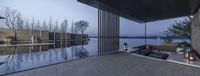 some chairs that are by a large glass pool and dock at night time as the sun goes down