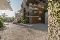 the walkway leading up to a luxury villa building with an outdoor area for seating and a balcony