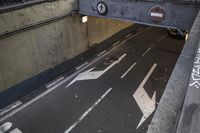 a road has arrows on it in a tunnel, while a sign points left and right