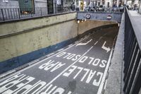 a road has arrows on it in a tunnel, while a sign points left and right