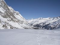 an image of a snow covered slope with some tracks in the snow with footprints from people going down the slope