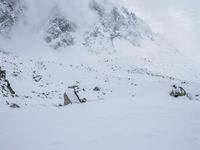 a skier stands atop a slope covered with snow and rocks in the distance, with a mountain in the background