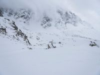 a skier stands atop a slope covered with snow and rocks in the distance, with a mountain in the background