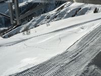 a ski slope has tracks left in the snow under a bridge or railing in the mountains