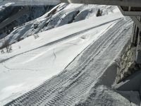 a ski slope has tracks left in the snow under a bridge or railing in the mountains