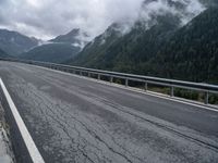 a long road leading over mountains and a valley under a cloudy sky on a dull day