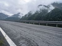 a long road leading over mountains and a valley under a cloudy sky on a dull day