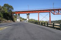 the red bridge is above the road and it is overpassed on either side