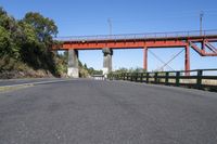 the red bridge is above the road and it is overpassed on either side