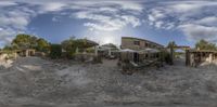 a 360 - ray view of an old building and a building and water feature with clouds in the background