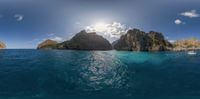 a view from a fish eye lens of the water and rocks in the foreground with a boat approaching