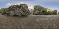 there is a lone mountain on the side of the water and rocks and grass all along this shore