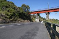 a bridge over the highway has an orange metal railing leading to it and people walking on the side