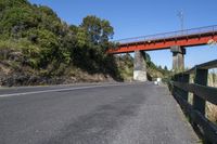 a bridge over the highway has an orange metal railing leading to it and people walking on the side