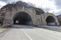 a tunnel that has cars in it near the side of the road with a rock formation