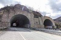 a tunnel that has cars in it near the side of the road with a rock formation