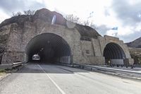 a tunnel that has cars in it near the side of the road with a rock formation