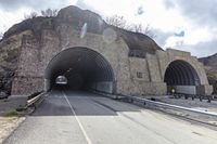 a tunnel that has cars in it near the side of the road with a rock formation