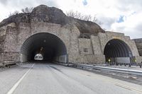 a tunnel that has cars in it near the side of the road with a rock formation