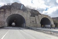 a tunnel that has cars in it near the side of the road with a rock formation