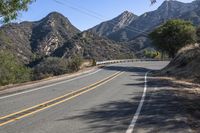 a street in the middle of a mountainside with a mountain range and yellow stripe lines