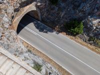 there is a long curved road next to the wall in the mountains under which is a road going under it