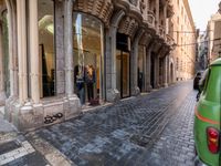 people in the street with clothes in store front window display windows and cobbles on either side