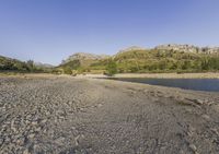 there are small rocks in the water along the shoreline of the river, near the mountains