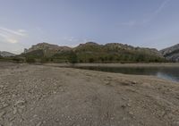 a rocky area with a body of water in the distance with mountains in the background