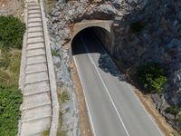 an empty tunnel on a mountain with cars going through it and stairs up the side