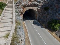 an empty tunnel on a mountain with cars going through it and stairs up the side