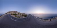 a panoramic view of an empty highway, in front of the ocean at sunset