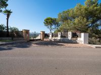 the driveway leading to the property is wide enough for parking it has a concrete fence that overlooks the backyard with trees, and blue skies