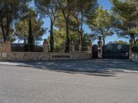 an ornate gate in front of the gate is set off by stone walls and trees